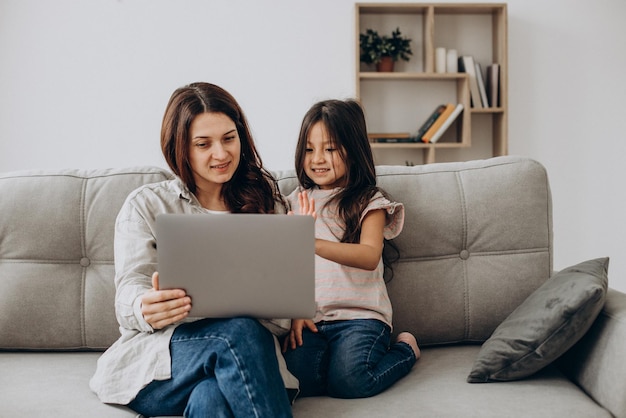 Mulher trabalhando online no laptop em casa com a filha