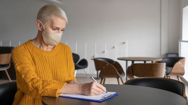 Foto mulher trabalhando sozinha enquanto se distancia socialmente de outros colegas de trabalho