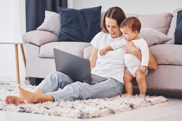 Mulher trabalhando usando laptop Mãe com sua filha está dentro de casa juntos
