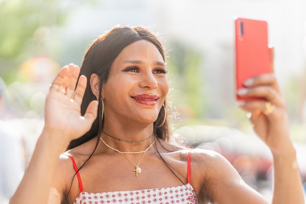 Mulher trans gesticulando olá para o celular