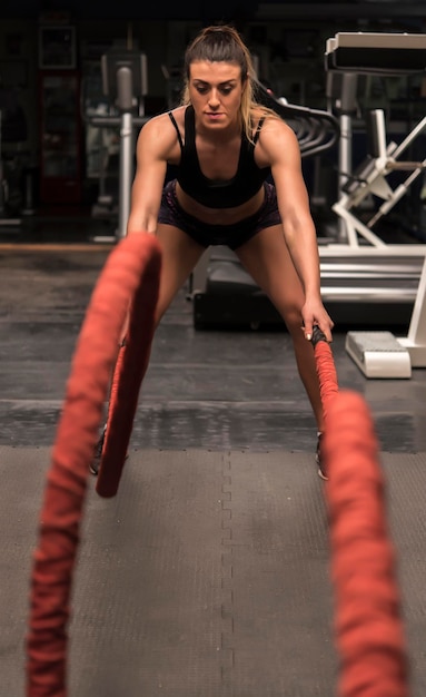 Mulher treinando com corda no ginásio.