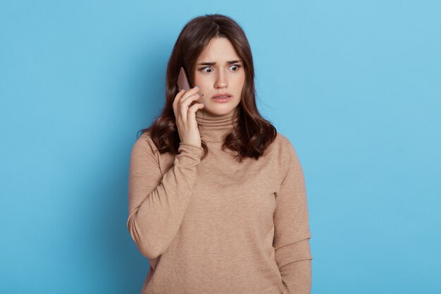 Mulher triste e preocupada falando ao telefone isolado