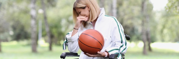 Mulher triste em cadeira de rodas está segurando o esporte de basquete na vida do conceito de pessoas