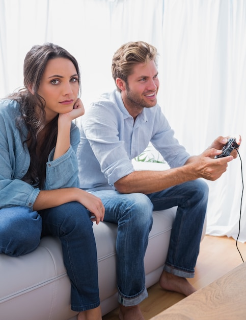 Mulher triste irritada que seu parceiro esteja jogando videogames