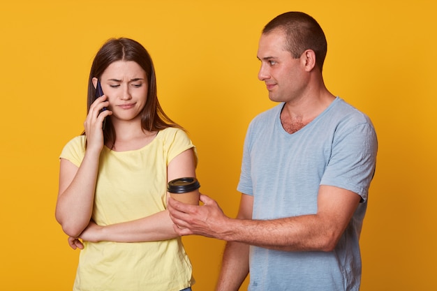 Mulher triste olha para baixo com expressão chateada enquanto fala via telefone inteligente