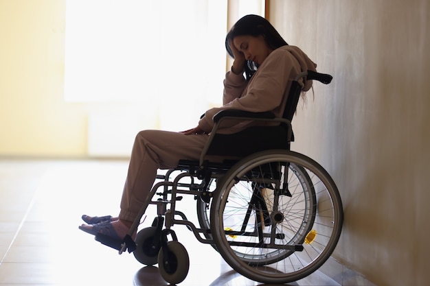 Foto mulher triste sentada em uma cadeira de rodas no centro de reabilitação. conceito de assistência psicológica para pessoas com deficiência