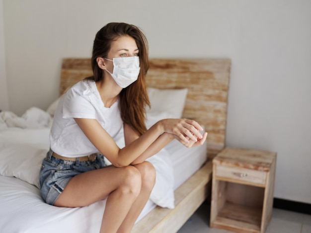 Mulher triste sentada na cama máscara médica dentro de casa em quarentena de pandemia de rosto