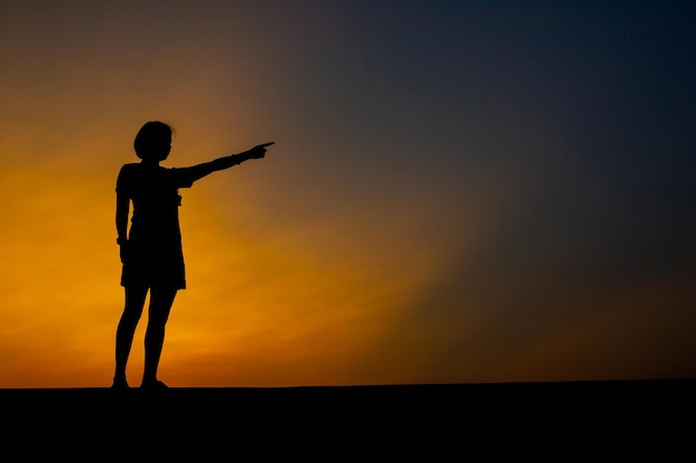 Foto mulher triste sozinha apontando para o pôr do sol no parque