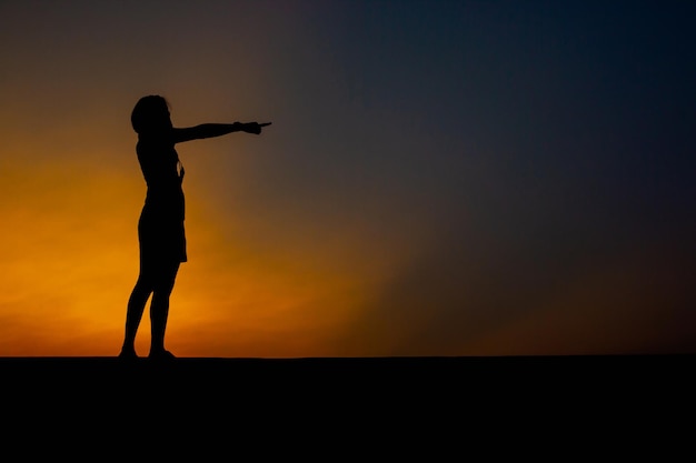 Foto mulher triste sozinha apontando para o pôr do sol no parque