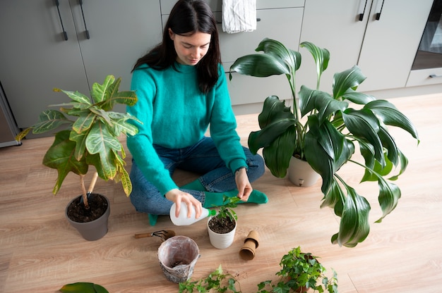 Foto mulher trocando os vasos de suas plantas em casa durante a quarentena