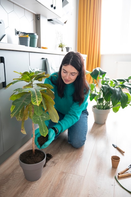Mulher trocando os vasos de suas plantas em casa durante a quarentena