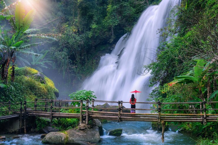 Foto mulher turista asiática de pé em uma ponte de bambu observando a cachoeira pha dok siew na tailândia
