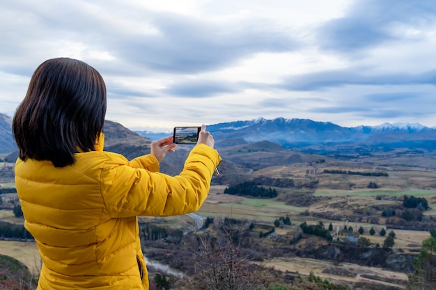 Foto mulher turista asiática tirando foto com celular em queenstown, ilha do sul, nova zelândia
