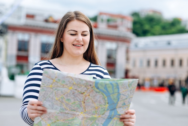 Mulher turista com um mapa nas mãos no meio da rua ao ar livre