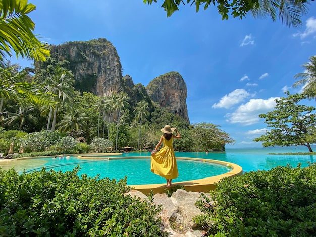 Mulher turista de vestido amarelo e chapéu viajando na praia de Railay Krabi Tailândia viagem de férias verão Wanderlust e conceito de férias