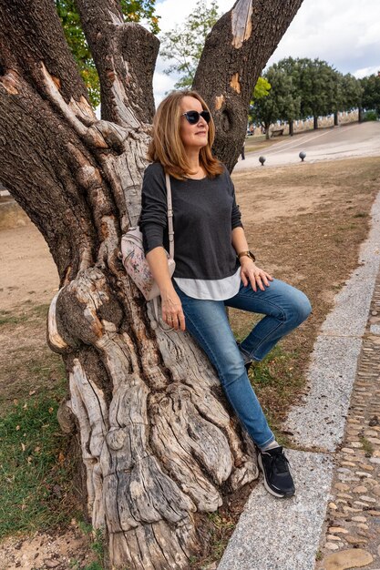 Mulher turista descansando no tronco de uma árvore muito velha na aldeia de Frias Burgos