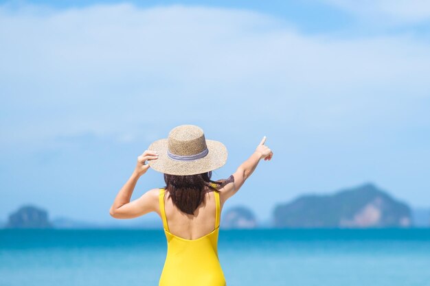 Mulher turista em maiô amarelo e chapéu viajante feliz tomando sol na praia Paradise no destino de ilhas desejo de viagem Ásia viagem férias de verão tropical e conceito de férias