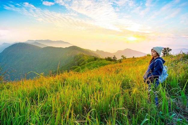 Mulher turista em pé no pico das montanhas e aprecia a vista com bela névoa e nascer do sol de