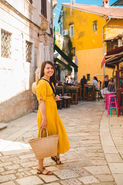 Mulher turista em vestido amarelo andando pela pequena rua da cidade croata
