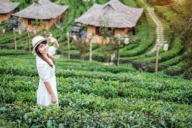 Mulher turista feliz de vestido branco desfruta do belo jardim de chá Viajante visitando a vila tailandesa de Ban Rak Mae Hong Son Tailândia viagem de férias e conceito de férias