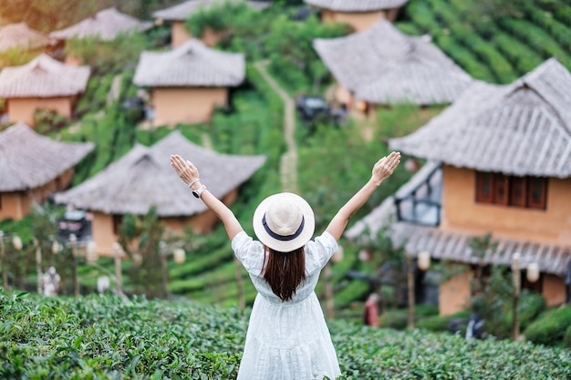 Mulher turista feliz de vestido branco desfruta do belo jardim de chá viajante visitando a vila tailandesa de ban rak mae hong son tailândia viagem de férias e conceito de férias