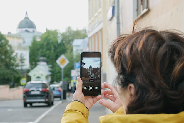 Mulher turista fotografa um marco enquanto caminha pela cidade