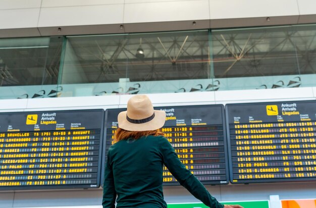 Mulher turista no aeroporto olhando as informações nas telas do terminal de conexão