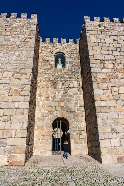 Mulher turista passando pelo portão de acesso ao castelo medieval de trujillo extremadura