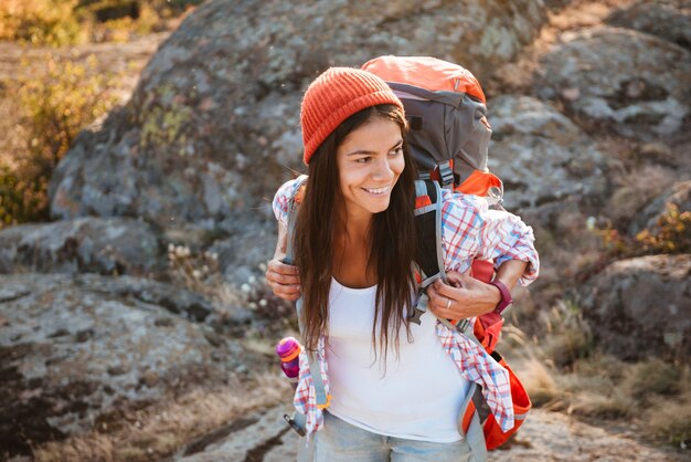 Foto mulher turista sorridente com mochila olhando para longe perto do cânion