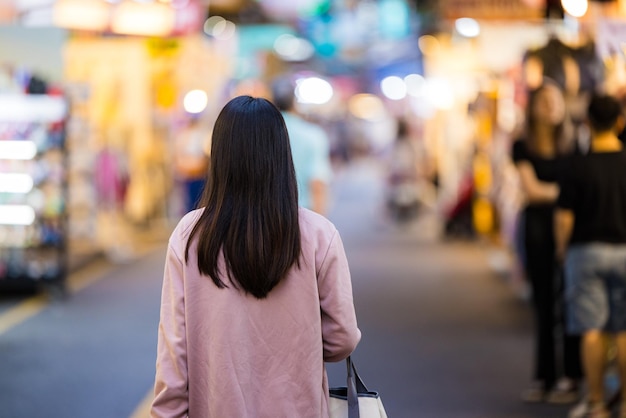 Mulher turista vai ao mercado de rua à noite em Taiwan