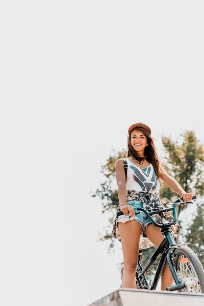 Foto mulher urbana com boné sentado na bicicleta