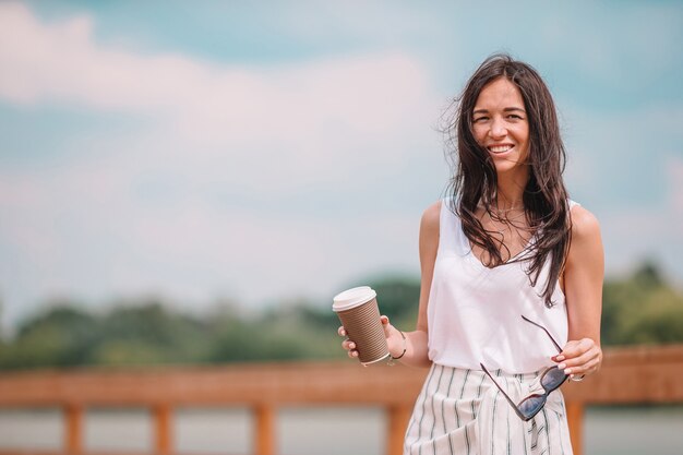 Mulher urbana jovem feliz bebendo café na cidade europeia.