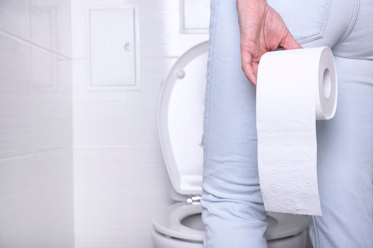 Foto mulher urinando com diarreia em um banheiro branco, em um banheiro com um rolo de papel branco com a mão