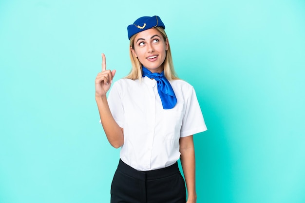 Foto mulher uruguaia aeromoça isolada em fundo azul apontando para cima e surpresa