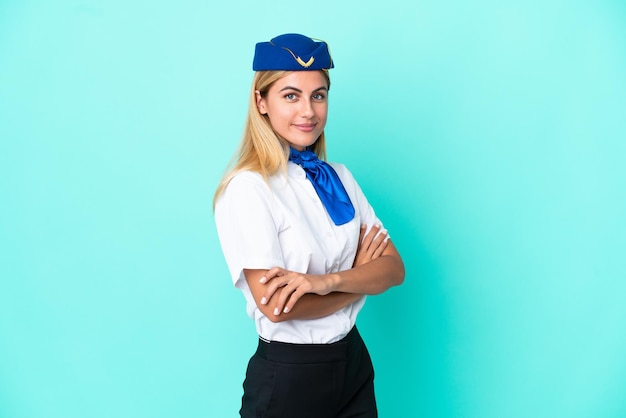 Mulher uruguaia aeromoça isolada em fundo azul com braços cruzados e olhando para a frente