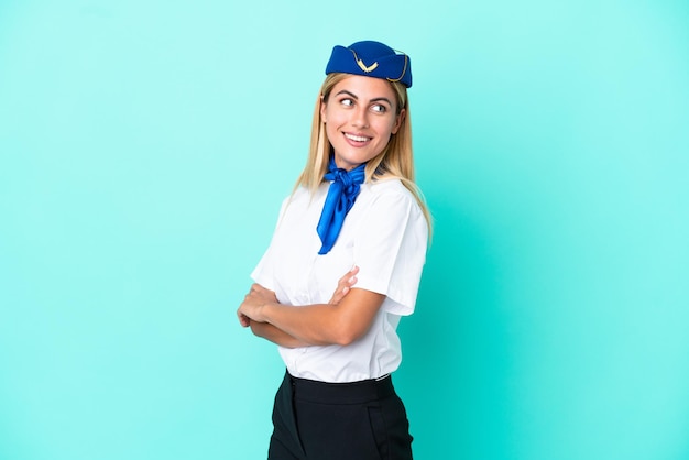 Mulher uruguaia aeromoça isolada em fundo azul com os braços cruzados e feliz