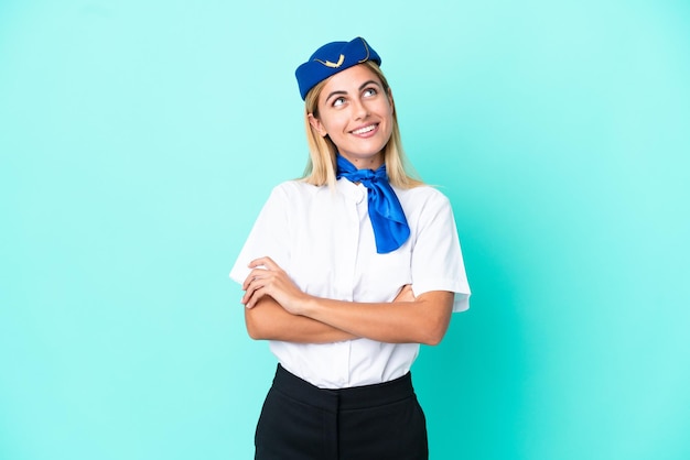 Mulher uruguaia aeromoça isolada em fundo azul olhando para cima enquanto sorria