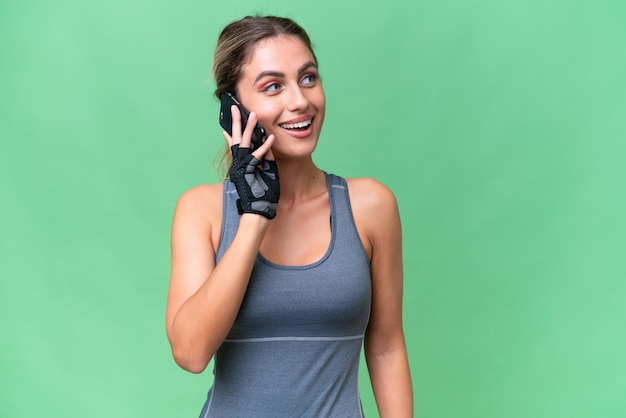 Mulher uruguaia bonita do esporte sobre fundo isolado, mantendo uma conversa com o telefone celular