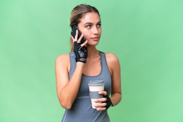 Mulher uruguaia bonita esporte sobre fundo isolado segurando café para levar e um celular