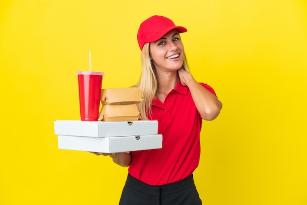 Foto mulher uruguaia de entrega segurando fast food isolada em fundo amarelo rindo