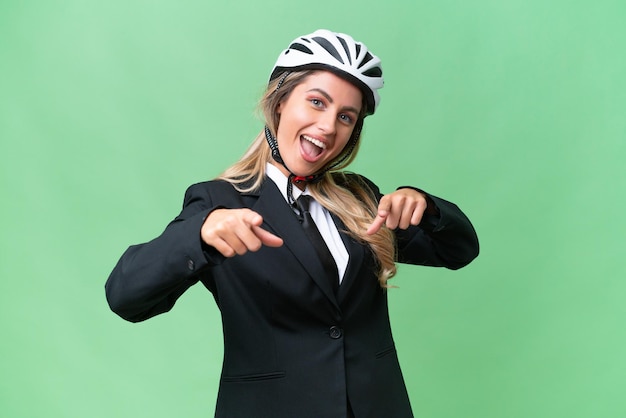 Mulher uruguaia de negócios usando um motociclista de capacete sobre fundo isolado, apontando para a frente e sorrindo