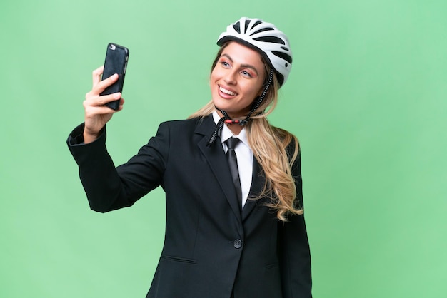 Mulher uruguaia de negócios usando um motociclista de capacete sobre fundo isolado fazendo uma selfie