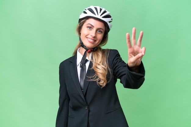 Mulher uruguaia de negócios usando um motociclista de capacete sobre fundo isolado feliz e contando três com os dedos