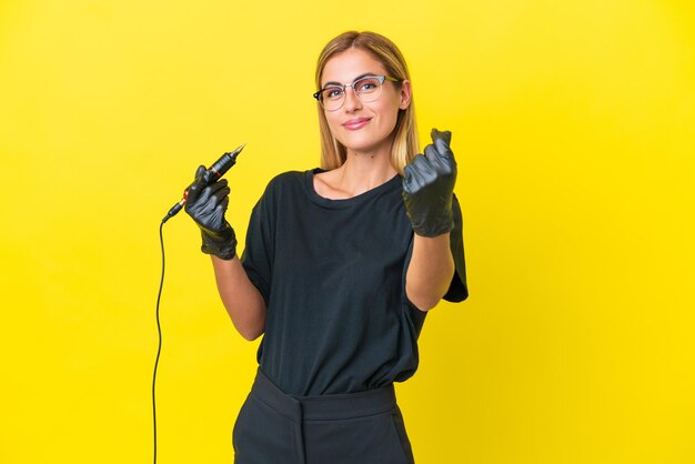 Mulher uruguaia do tatuador isolada em fundo amarelo fazendo gesto de dinheiro