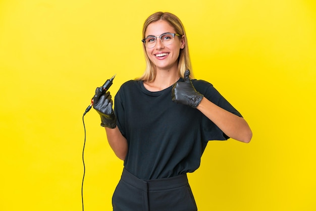 Mulher uruguaia tatuadora isolada em fundo amarelo dando um polegar para cima gesto