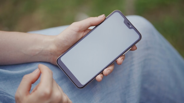 Mulher usa as mãos digitando em telefones celulares e tela de toque, trabalhando com dispositivos de aplicativos de estilo vintage no parque