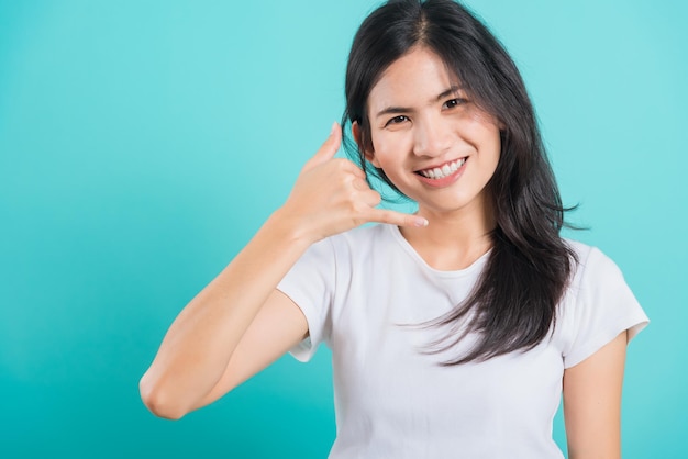 Mulher usa camiseta branca sorri dentes brancos fazendo me chamar de gesto