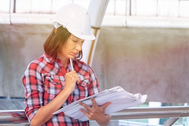 Foto mulher usa chapéu de segurança branco está trabalhando no canteiro de obras