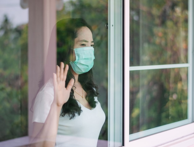 Mulher usa máscara e fica em casa para evitar a disseminação do coronavírus