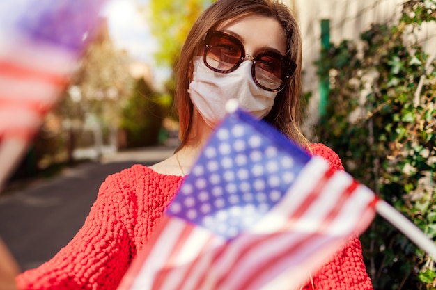 Mulher usa máscara protetora ao ar livre comemora o Dia da Independência dos EUA com bandeiras durante o coronavírus covid-19